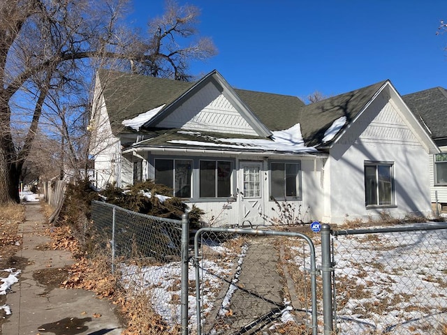 view of front of property featuring a fenced front yard, a gate, and a shingled roof