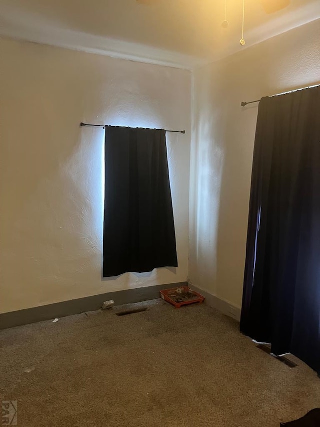 empty room featuring carpet floors, visible vents, and baseboards