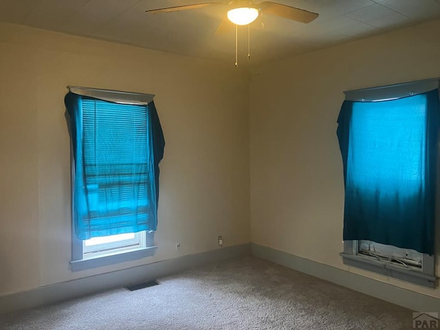 spare room featuring ceiling fan, carpet, visible vents, and baseboards