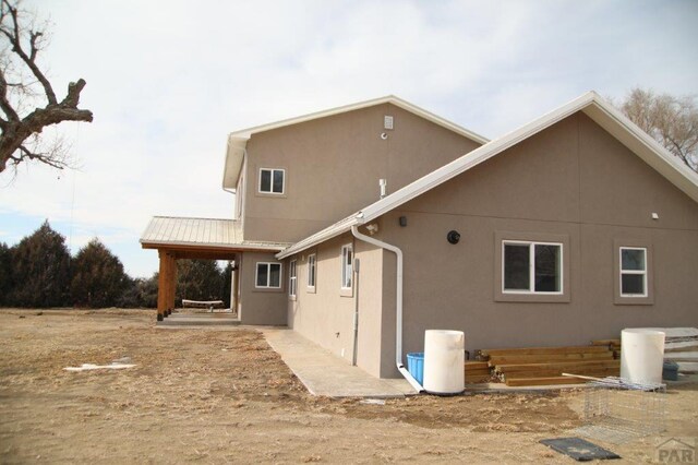 back of property featuring metal roof and stucco siding