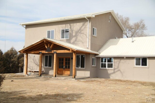 back of house featuring metal roof and stucco siding