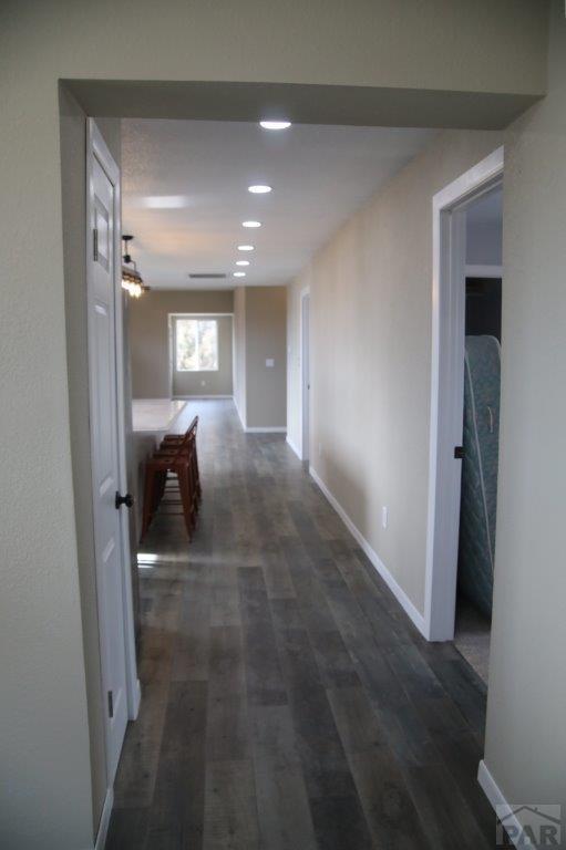 hallway with dark wood-type flooring, recessed lighting, and baseboards