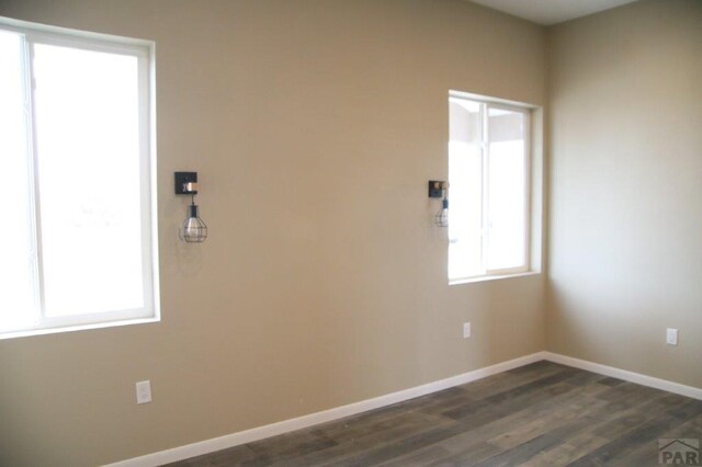 unfurnished room with dark wood-type flooring and baseboards