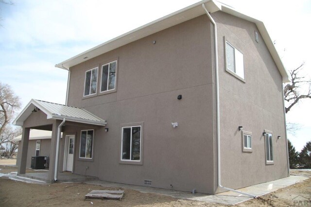 rear view of house featuring a patio area, metal roof, central AC, and stucco siding