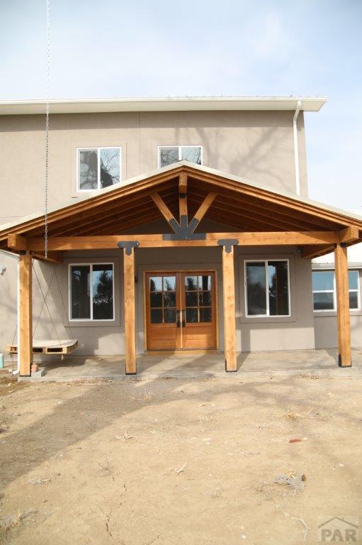 back of property featuring central AC, metal roof, and stucco siding