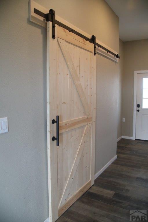 doorway to outside with dark wood-type flooring, baseboards, and a barn door