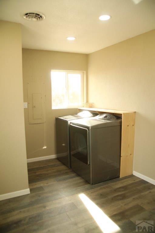 laundry area with dark wood-style floors, visible vents, washing machine and dryer, laundry area, and baseboards