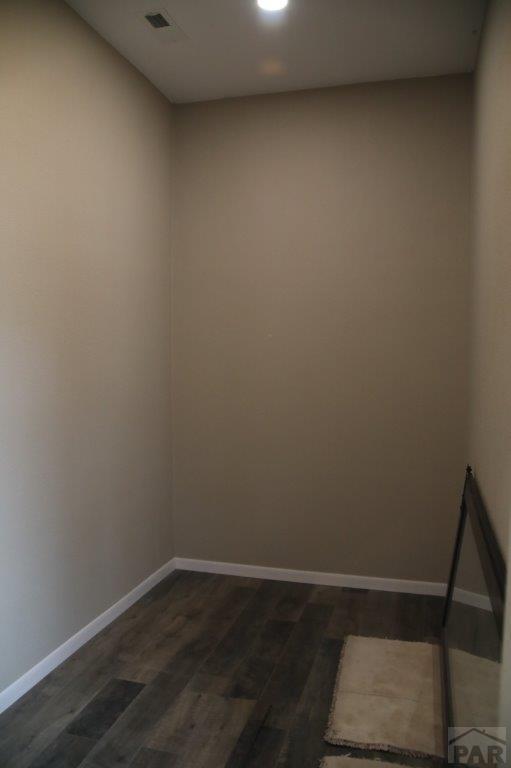 unfurnished room with baseboards and dark wood-type flooring