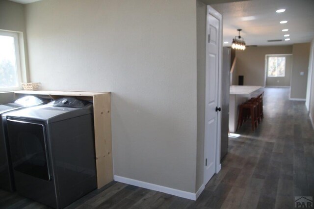 laundry area with dark wood-style floors, laundry area, baseboards, and washer and dryer