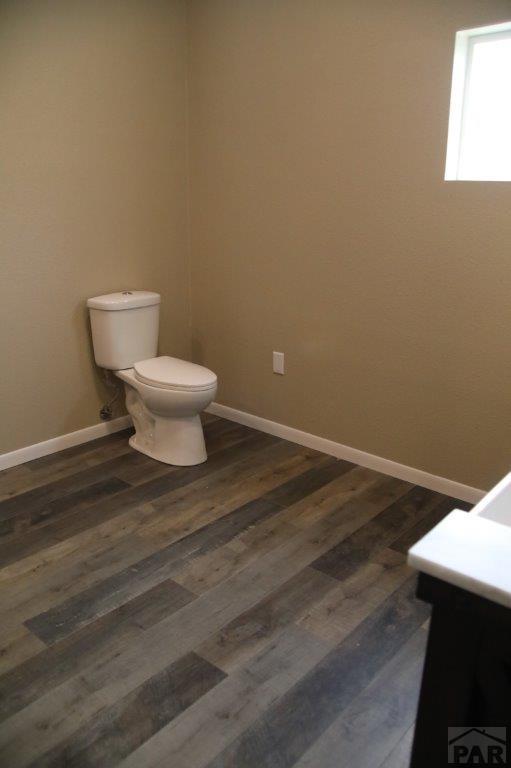 bathroom with baseboards, vanity, toilet, and wood finished floors