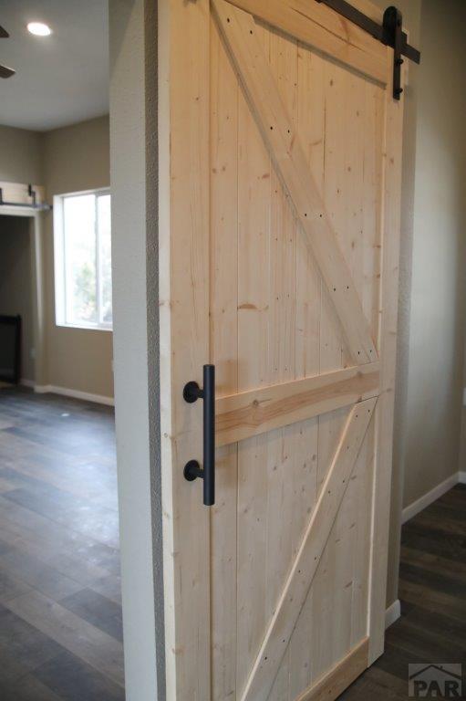 interior details with a barn door, wood finished floors, and baseboards