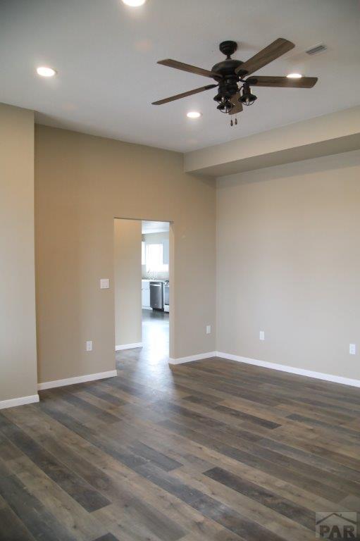 unfurnished room with dark wood-style flooring, visible vents, and baseboards