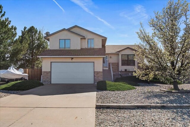 view of front of property featuring an attached garage, brick siding, fence, driveway, and stucco siding