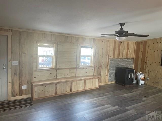 8417 3r Rd, Beulah, CO 80123 - unfurnished living room with wooden walls, a wood stove, dark wood-type flooring, and a ceiling fan
