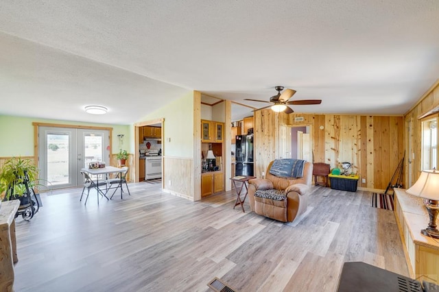 8417 3r Rd, Beulah, CO 80123 - living room featuring plenty of natural light, wood walls, light wood-type flooring, ceiling fan, and vaulted ceiling