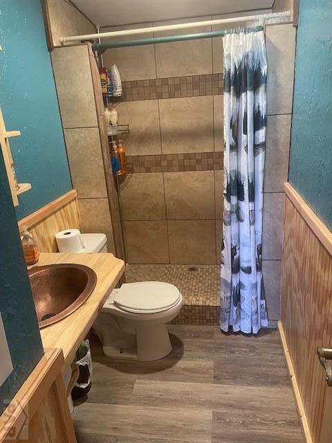 8417 3r Rd, Beulah, CO 80123 - bathroom featuring a sink, toilet, a shower stall, wood finished floors, and a wainscoted wall