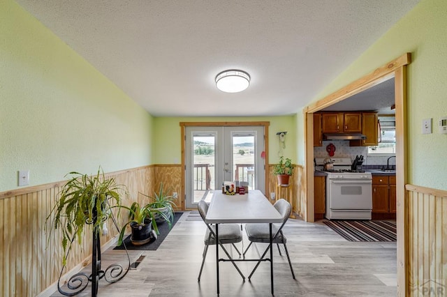 8417 3r Rd, Beulah, CO 80123 - dining space featuring light wood-type flooring, a wainscoted wall, french doors, and wood walls