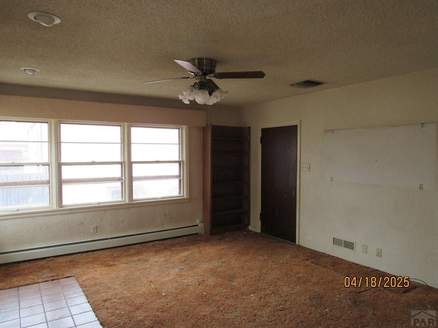 carpeted empty room with baseboard heating, a textured ceiling, and visible vents