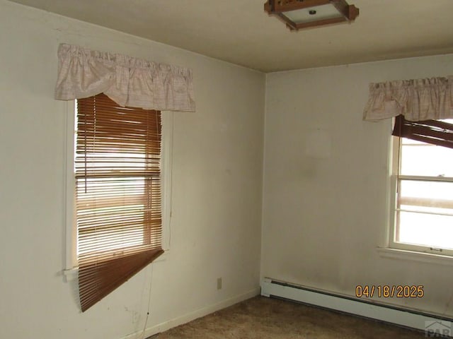 carpeted spare room with a baseboard heating unit