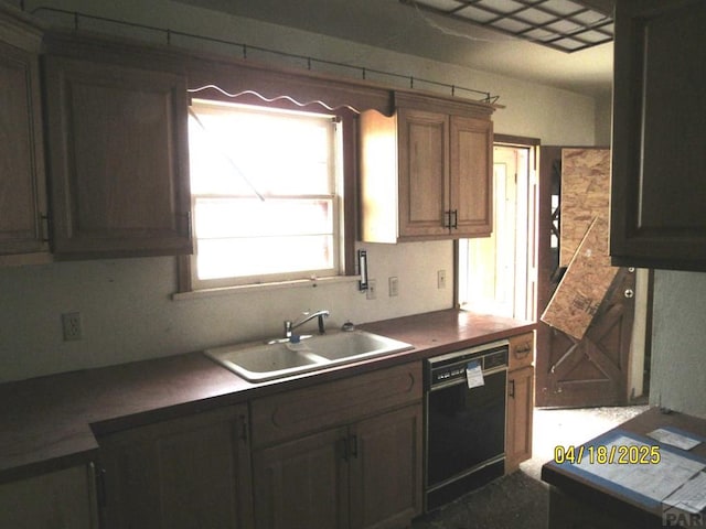 kitchen with dark countertops, dishwasher, and a sink