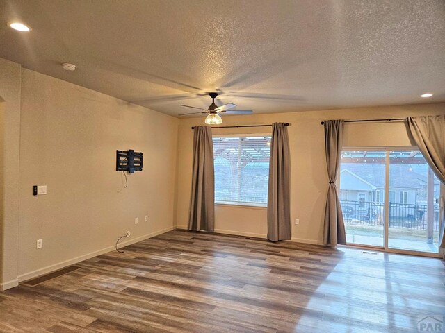 unfurnished room featuring ceiling fan, a textured ceiling, baseboards, and wood finished floors