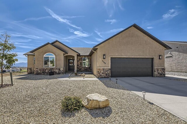 view of front of house featuring an attached garage, stone siding, concrete driveway, and stucco siding