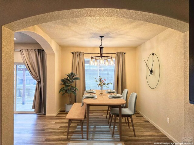 dining room featuring dark wood-style floors, arched walkways, a textured ceiling, and baseboards