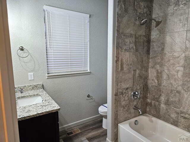 full bathroom featuring visible vents, toilet, vanity, wood finished floors, and  shower combination