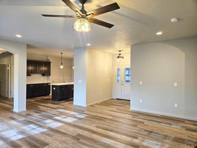 kitchen featuring arched walkways, a kitchen island, open floor plan, hanging light fixtures, and light countertops