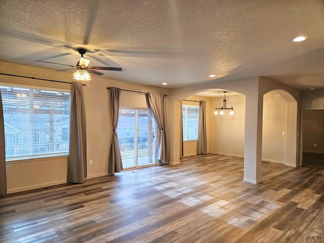 interior space with baseboards, arched walkways, ceiling fan, wood finished floors, and recessed lighting