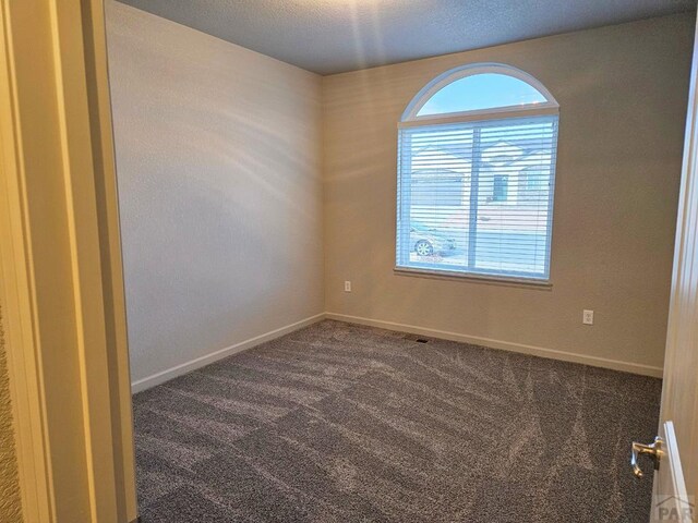 empty room featuring dark carpet and baseboards