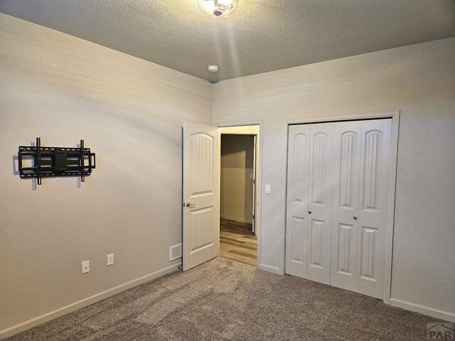 bedroom featuring carpet floors, a closet, a textured ceiling, and baseboards