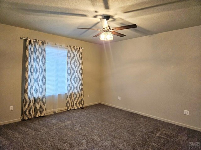 unfurnished room with a ceiling fan, dark colored carpet, a textured ceiling, and baseboards