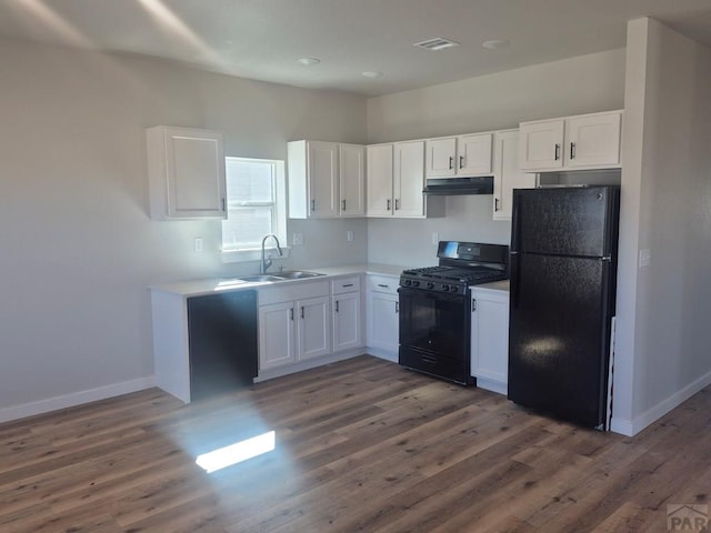 kitchen featuring black appliances, under cabinet range hood, white cabinetry, and a sink