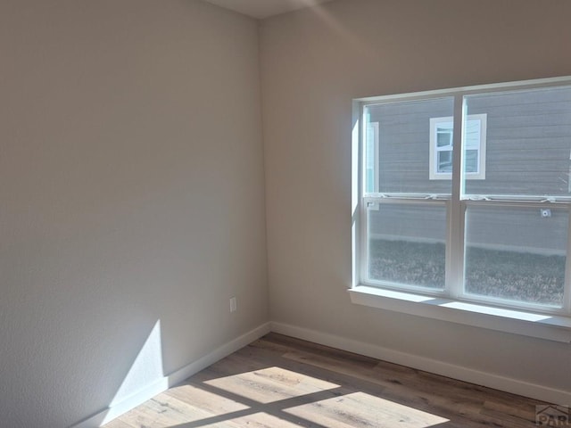 unfurnished room featuring baseboards and wood finished floors