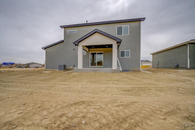 rear view of property featuring a patio, central AC unit, and stucco siding
