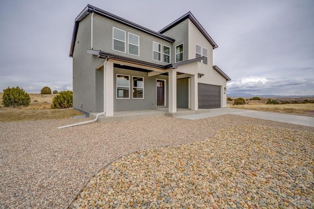 view of front of home featuring driveway, covered porch, a garage, and stucco siding