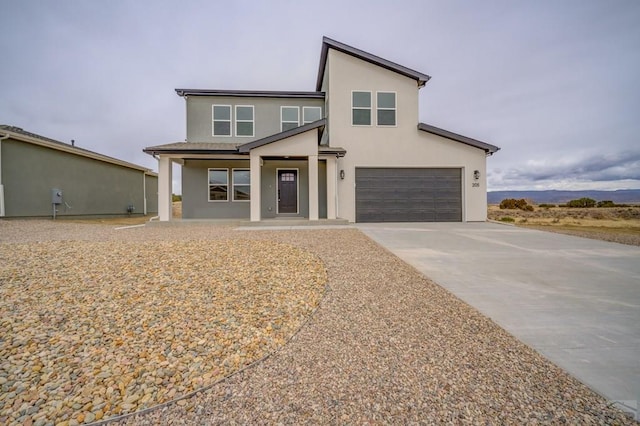 modern home with a garage, driveway, a porch, and stucco siding