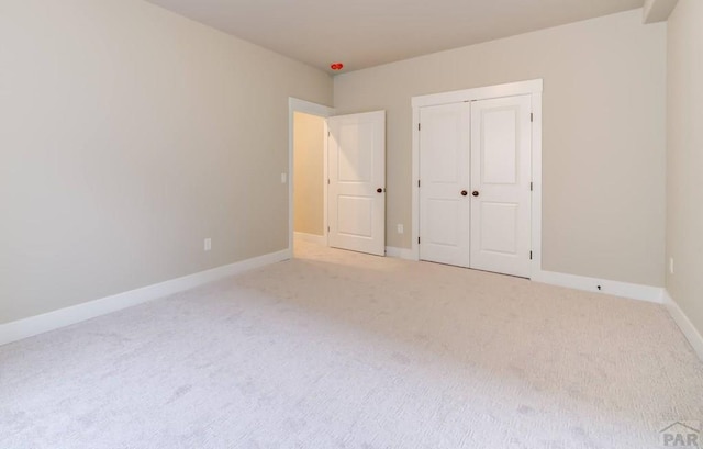 unfurnished bedroom with carpet floors, baseboards, and a closet