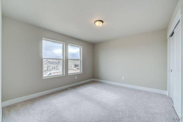 spare room with light carpet, visible vents, and baseboards