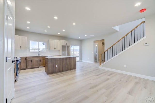 kitchen featuring white cabinetry, light countertops, electric stove, a center island, and brown cabinetry