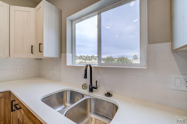 kitchen with light countertops, tasteful backsplash, and a sink