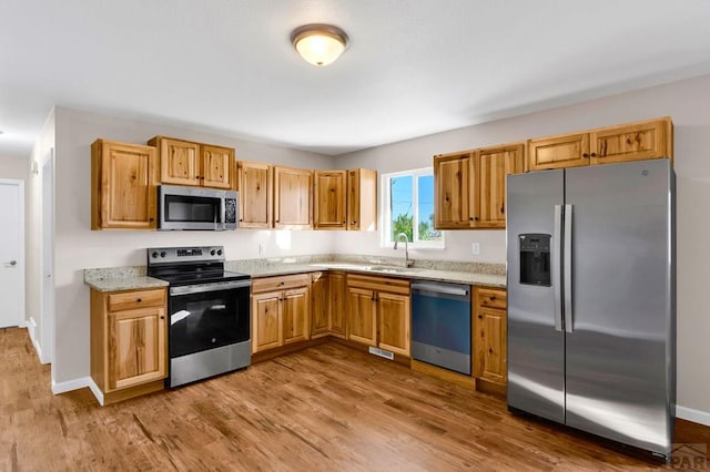 1510 24 1/4 Ln, Pueblo, CO 81006 - kitchen with appliances with stainless steel finishes, a sink, wood finished floors, and light stone countertops