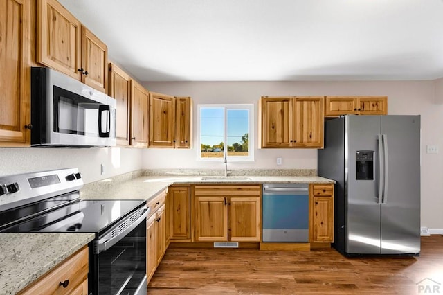 1510 24 1/4 Ln, Pueblo, CO 81006 - kitchen featuring stainless steel appliances, a sink, dark wood-style flooring, and light stone countertops