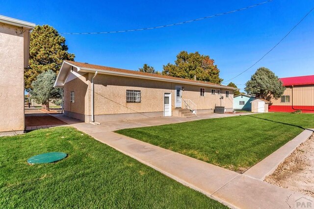 1510 24 1/4 Ln, Pueblo, CO 81006 - back of house with entry steps, a lawn, stucco siding, a patio, and an outbuilding
