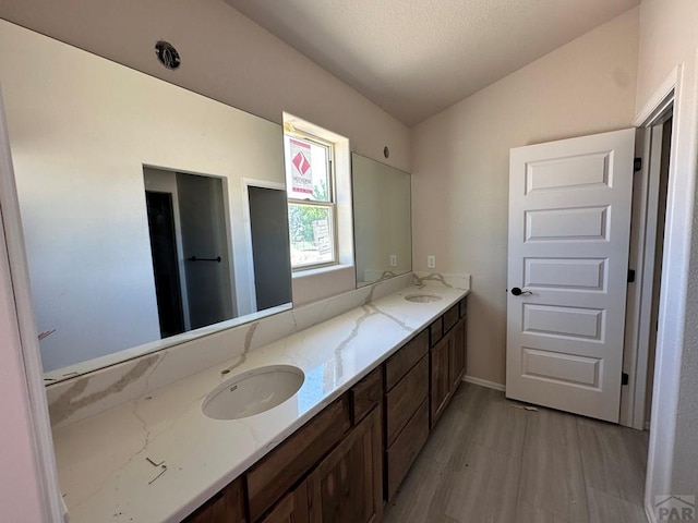 962 E Sandusky Dr, Pueblo West, CO 81007 - full bath featuring double vanity, wood finished floors, vaulted ceiling, and a textured ceiling