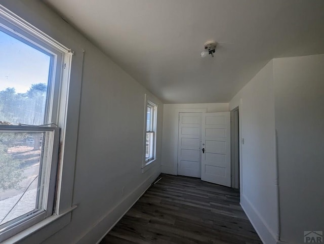 hallway featuring dark wood-style flooring and baseboards