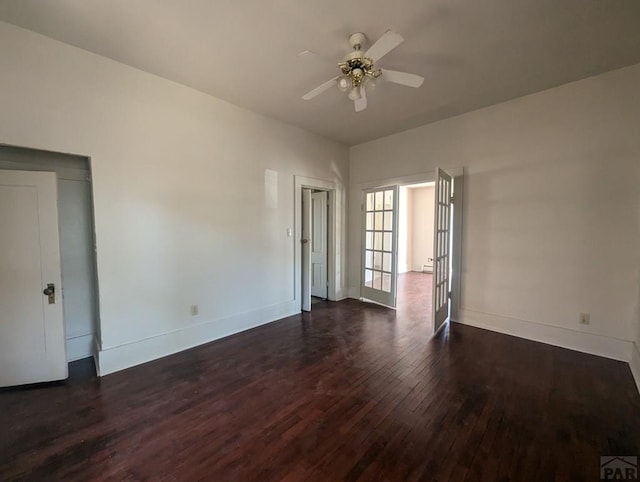 empty room featuring dark wood finished floors, baseboards, and ceiling fan