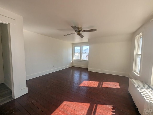 unfurnished room featuring a ceiling fan, baseboards, and dark wood-style flooring