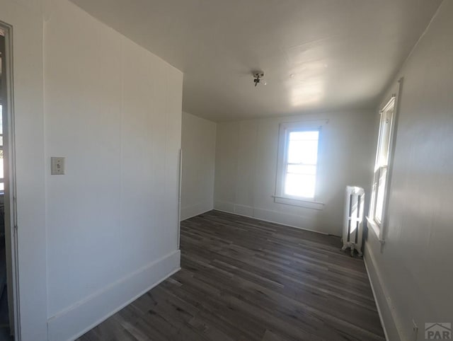 unfurnished room featuring radiator, dark wood finished floors, and baseboards